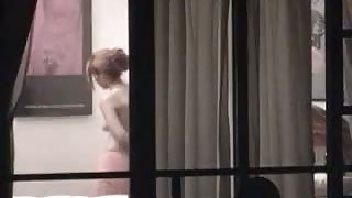 Sexy blonde stripping next to a window caught on voyeur cam