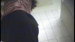 A milf is putting on a yellow striped bikini in the swimming pool changing room